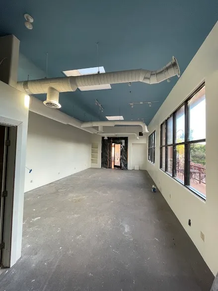 Commercial interior with freshly painted blue ceiling and white exposed ductwork