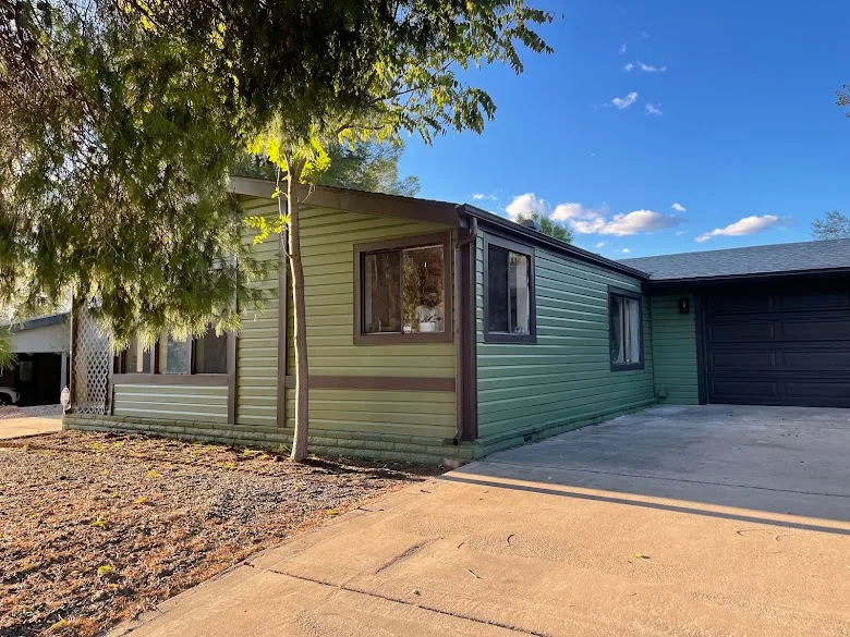 Home exterior repainted in sage green siding with dark brown trim and garage door by JLM Painting